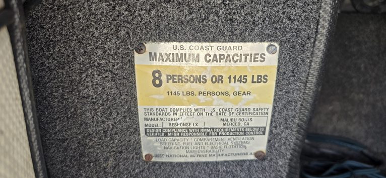 U.S. Coast Guard capacity plate showing 8 persons or 1145 lbs limit.