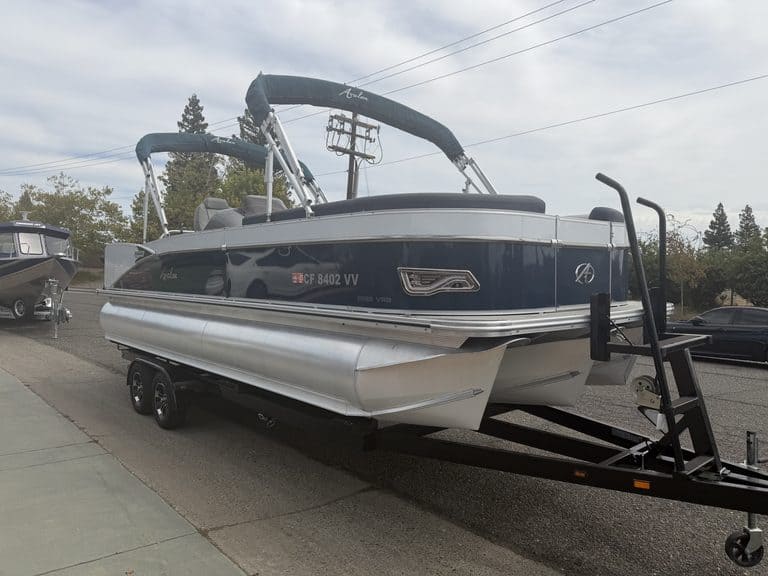 Luxury Avalon Catalina pontoon boat on trailer at dealership lot.