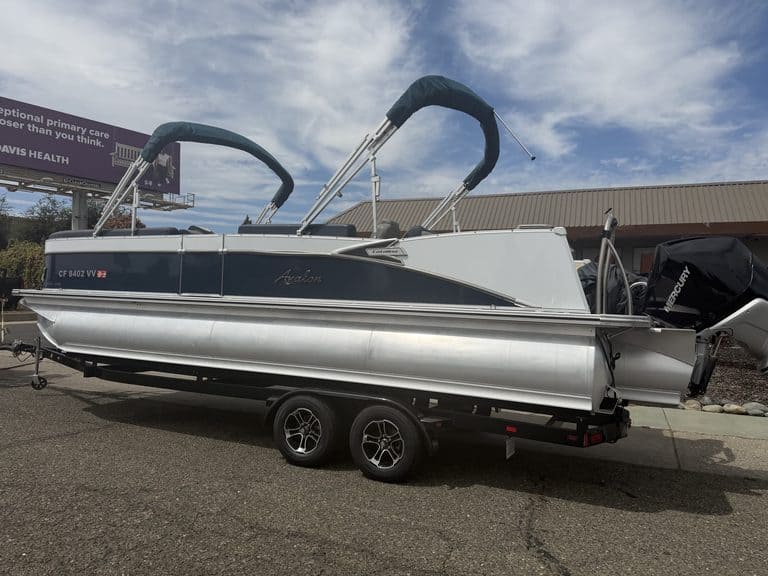 Luxury Avalon Catalina pontoon boat on trailer with outboard motor.