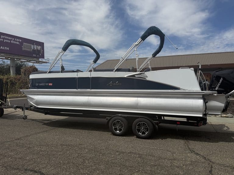 Luxury Avalon Catalina pontoon boat on trailer with outboard motor.