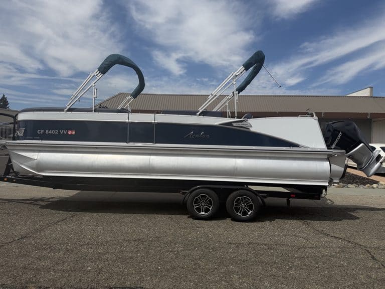 Luxury Avalon Catalina pontoon boat on trailer with outboard motor.
