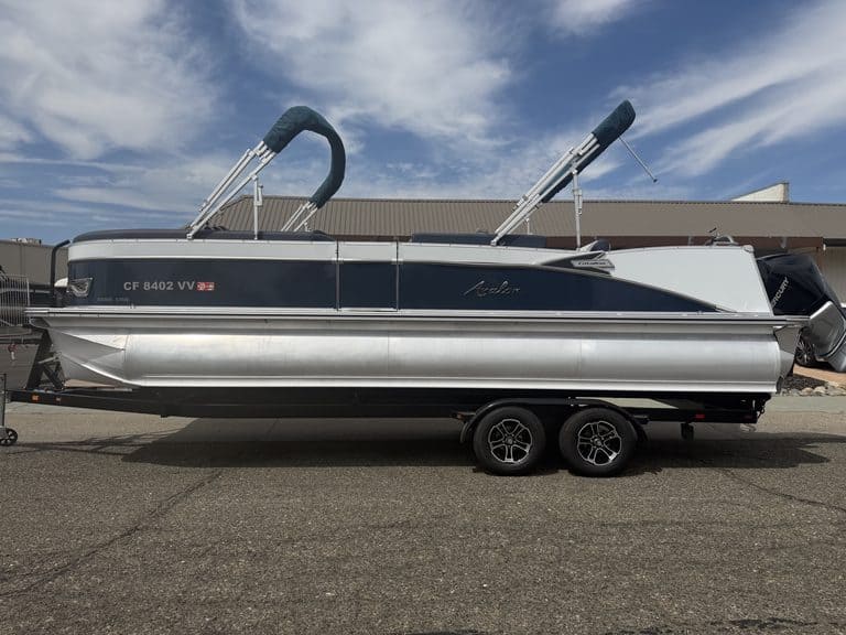 Luxury Avalon Catalina pontoon boat on trailer with blue sky background.