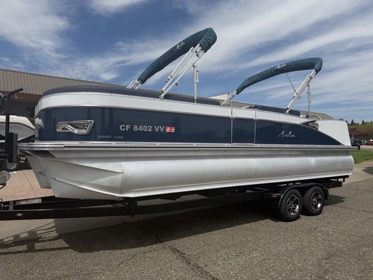Luxury Avalon Catalina pontoon boat on trailer with blue sky background.