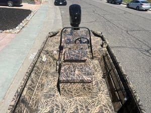 Aluminum fishing boat with camouflage pattern and outboard motor.