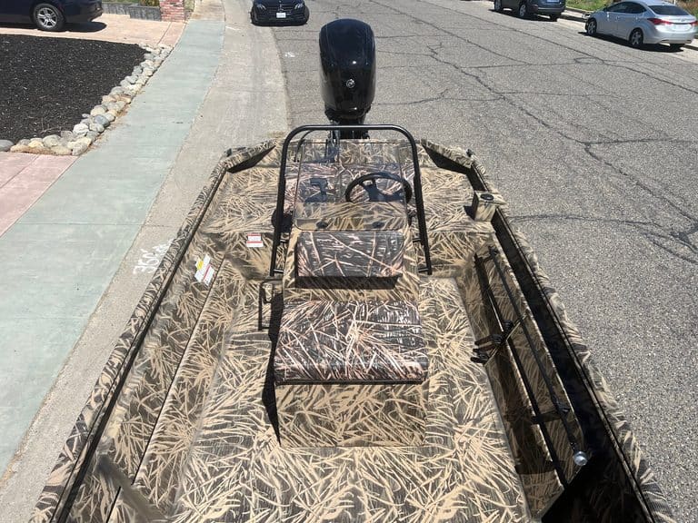 Aluminum fishing boat with camouflage pattern and outboard motor.