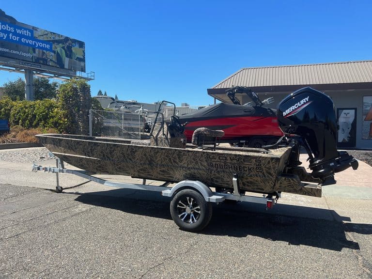 Camouflage Roughneck fishing boat with Mercury outboard motor on trailer.