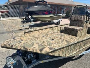 Camouflage utility boat with seating and trailer for outdoor use.