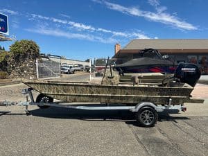 Camouflage Roughneck fishing boat with Mercury outboard motor on trailer.