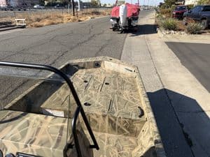 Camouflage boat parked on sidewalk in urban area.