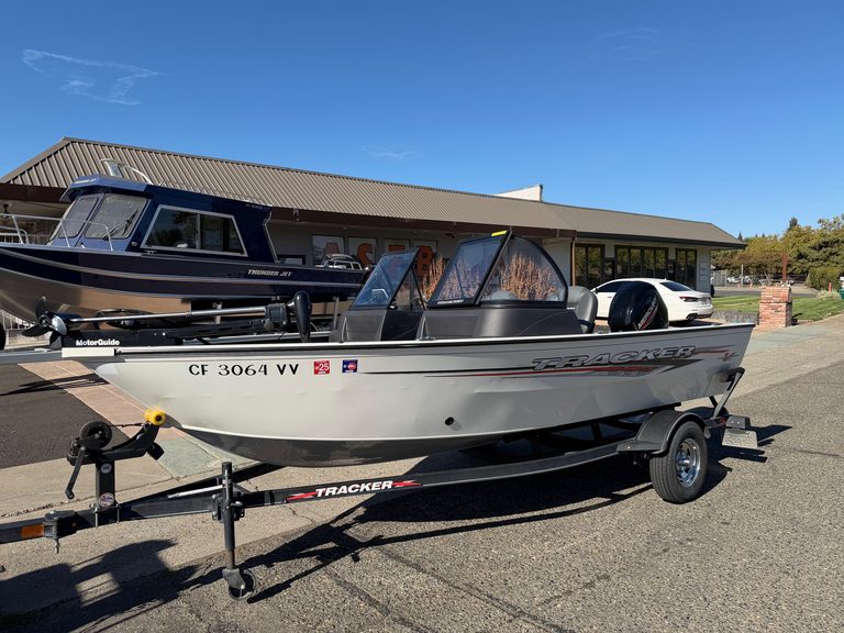 Tracker Pro boat with Mercury 60HP engine on trailer outside dealership.