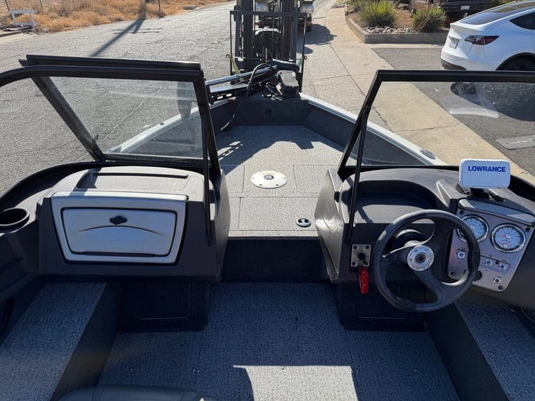 Boat dashboard with steering wheel and controls for fishing or leisure.
