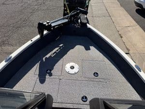 Close-up of boat deck with trolling motor and storage compartments.