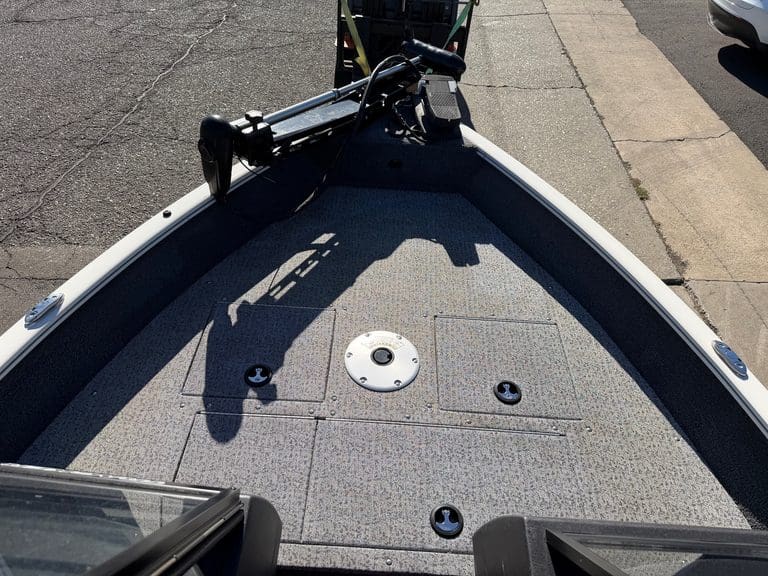 Close-up of boat deck with trolling motor and storage compartments.