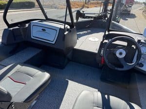 Boat cockpit with steering wheel and dashboard in sunlight.