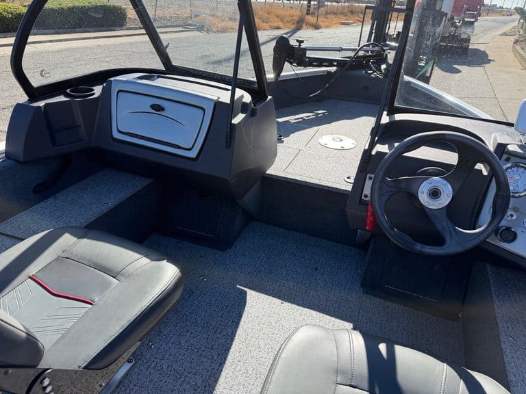 Boat cockpit with steering wheel and dashboard in sunlight.