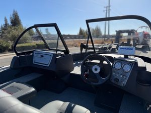 Boat dashboard with steering wheel and navigation instruments.