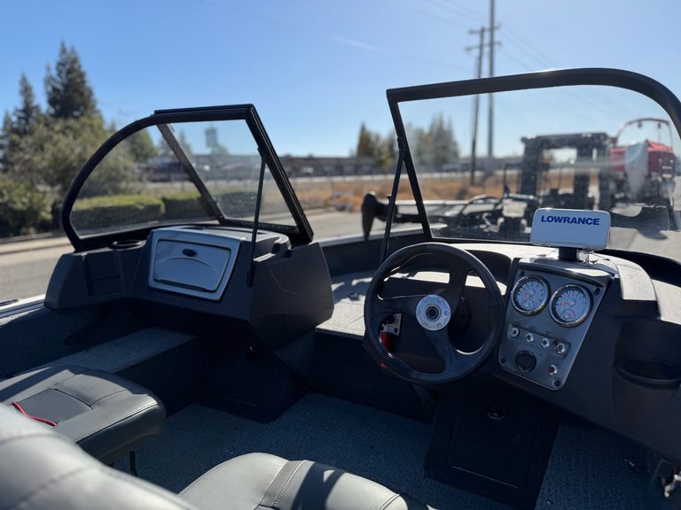 Boat dashboard with steering wheel and navigation instruments.