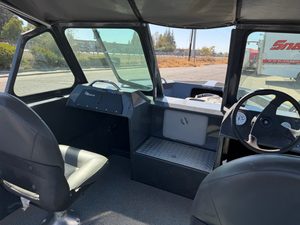 Interior view of a boat cockpit with steering wheel and dashboard.