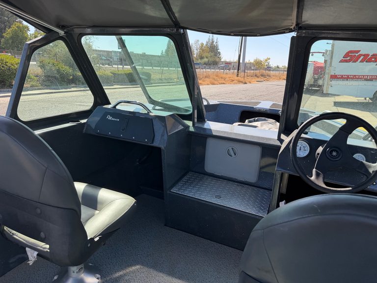 Interior view of a boat cockpit with steering wheel and dashboard.