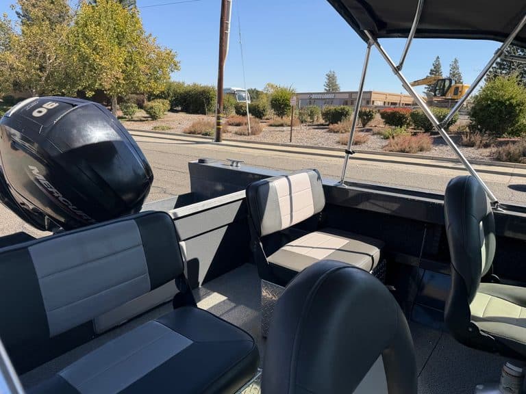 Pontoon boat with seating and outboard motor on a sunny day.