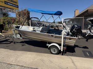 Westcoaster boat with canopy on trailer at dealership.