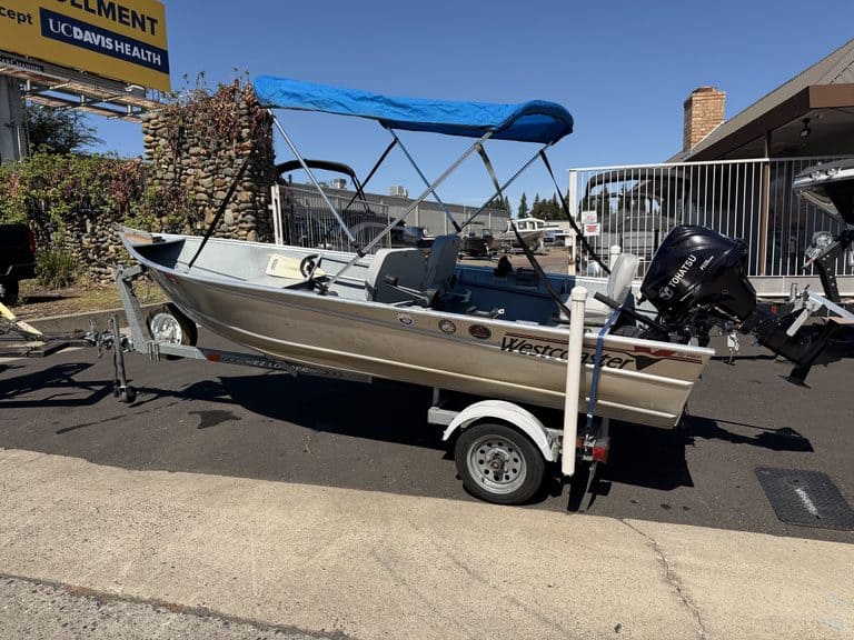 Westcoaster boat with canopy on trailer at dealership.