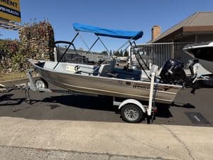 Westcoaster boat on trailer with outboard motor and blue canopy.