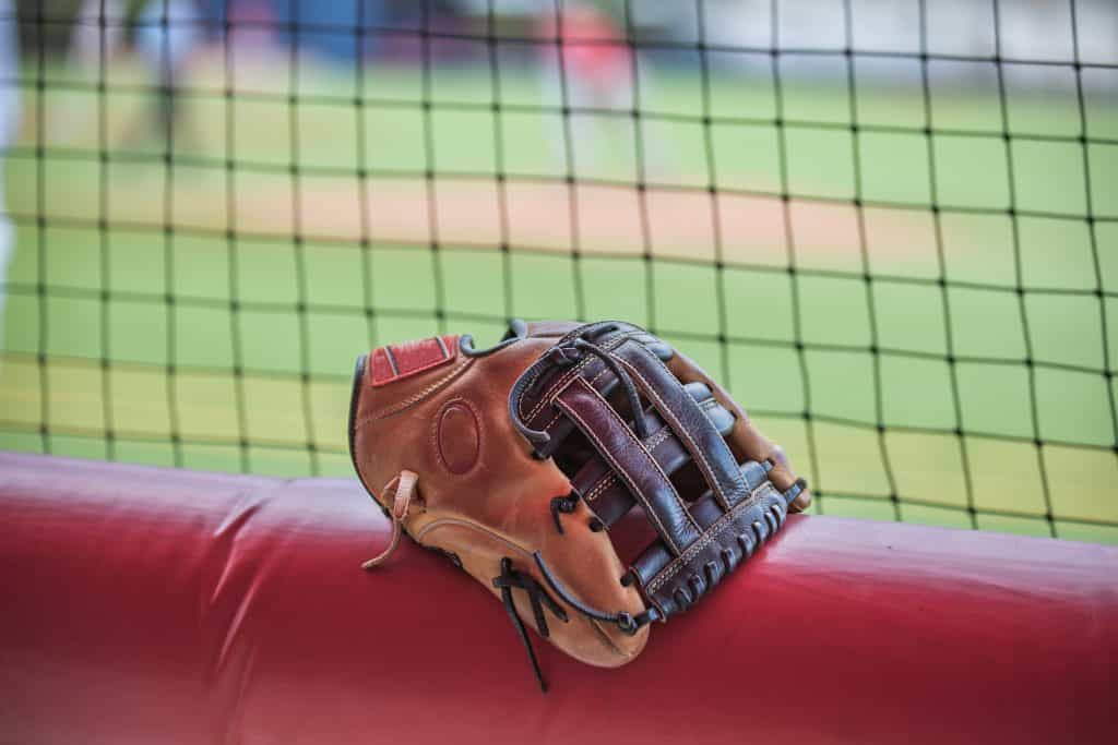 Baseball glove resting on dugout rail at batting cages.