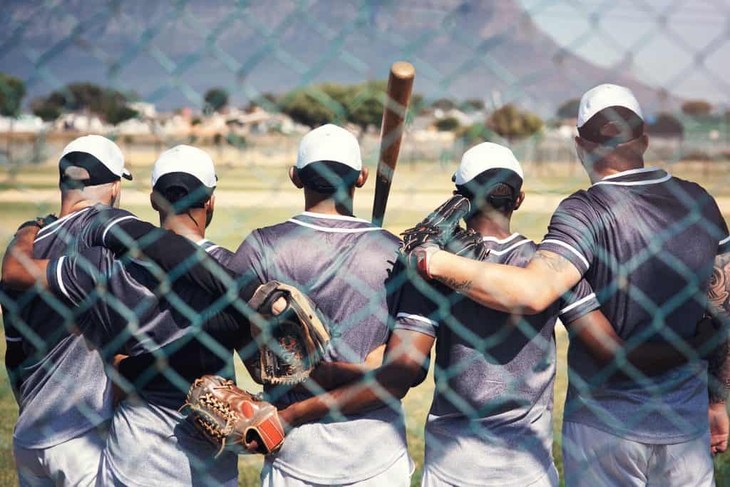 Young baseball players at batting cages preparing for game.