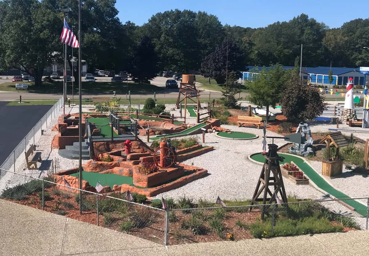 Miniature golf course with obstacles and slides at Bat'n Club in a sunny outdoor setting.