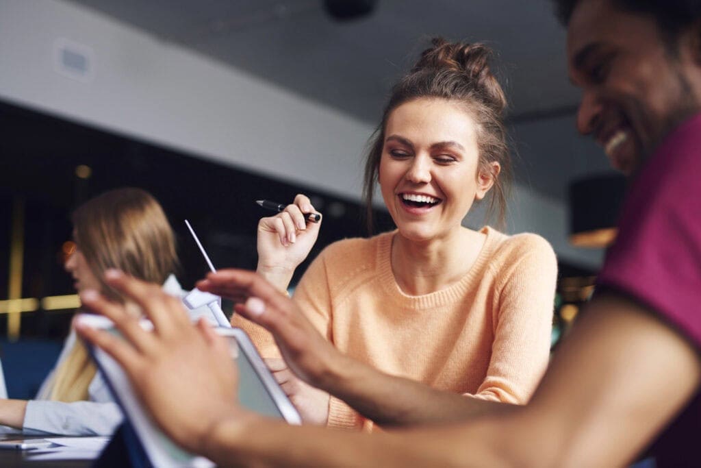 Woman smiles and laughs with man working on ipad