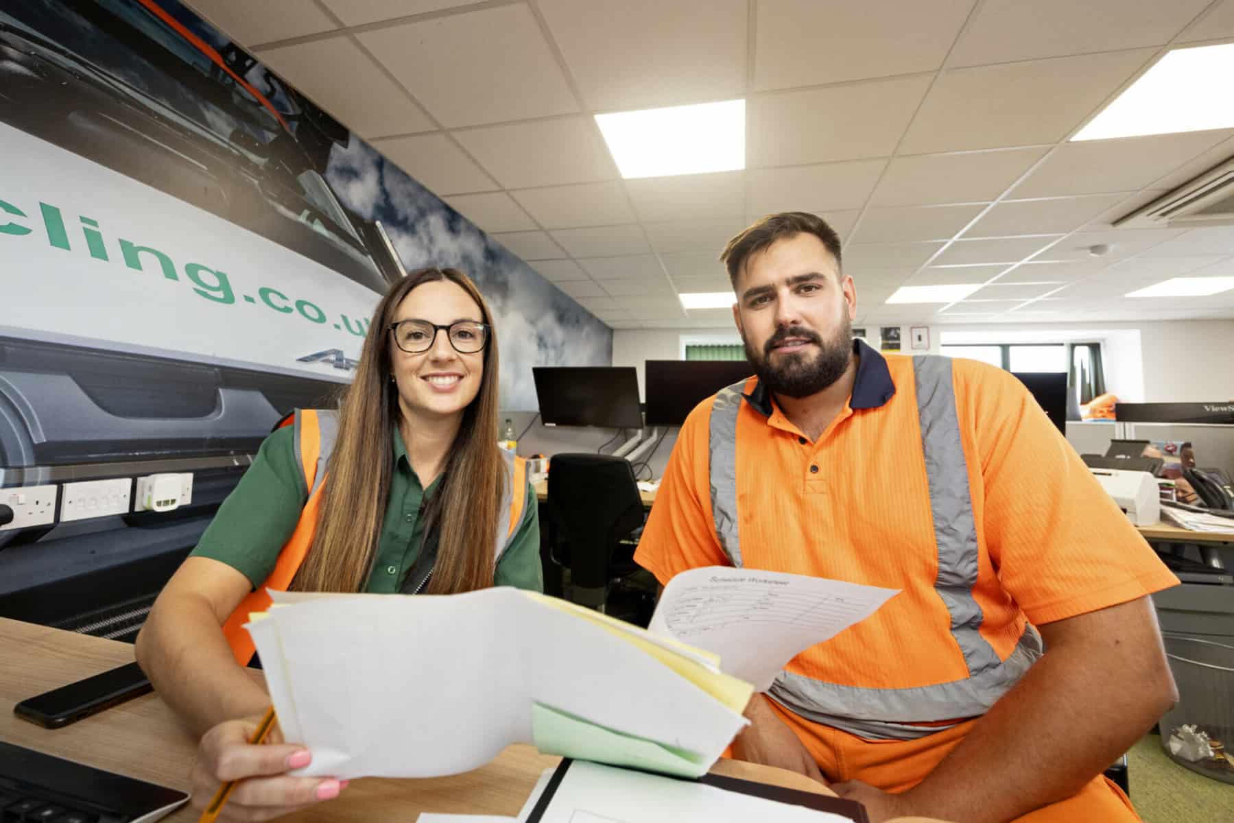 Two Countrystyle workers hold paperwork and smile