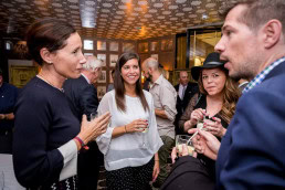 A group of people talking and drinking wine during a dinner event for Hispania Brussels