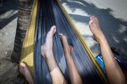 Close up flash street photograph of two people's legs on a hammock in the beach in Miami