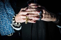 Close up flash street photograph of an elder woman's hands interlaced with each other