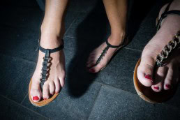 Close up flash street photograph of three feet wearing sandals in Budapest