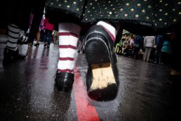 Close up flash street photograph of the sole of a woman's shoe while she walks away in Munich