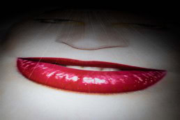 Close up flash street photograph of a billboard showing a face with red lips