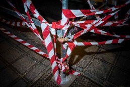 Close up flash street photograph of a scaffolding holding red and white tape