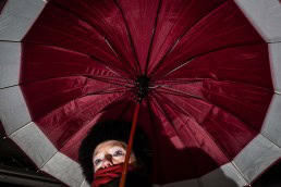 Close up flash street photograph of a woman under an umbrella taken from below