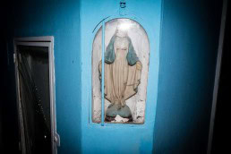 Close up flash street photograph of the statue of virgin Marie behind a glass pedestal