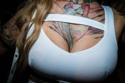 Close up flash street photograph of a woman's chest which has a big tattoo in Miami