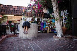 A girl wearing a skirt trying to enter a water well in the streets