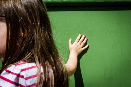 Street scene of a girl's hand with pink nails touching a green wall in Brussels