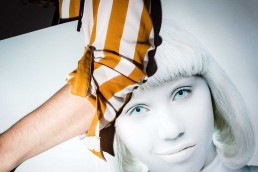 Close up flash street photograph of a woman's arm holding a bag with a woman's face stamped on it