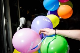 Close up flash street photograph of a hand carrying a bunch of colored balloons