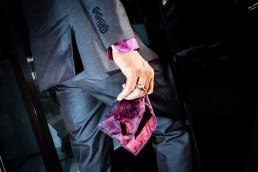Close up flash street photograph of a man wearing a suit carrying a violet handkerchief