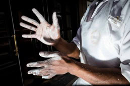 Close up flash street photograph of black man with his hands covered in white flour in Brussels