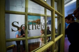 Visitors seen through a window during an art exhibition event by Sotheby's in Brussels