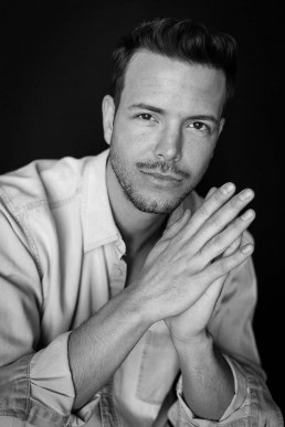 Black and white headshot portrait of a man wearing a jean shirt